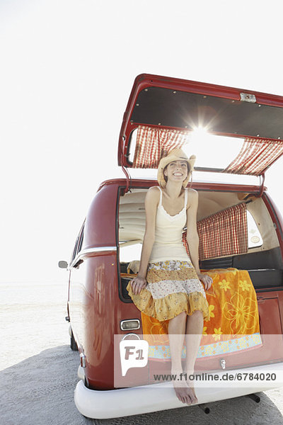 Young woman sitting in van on beach