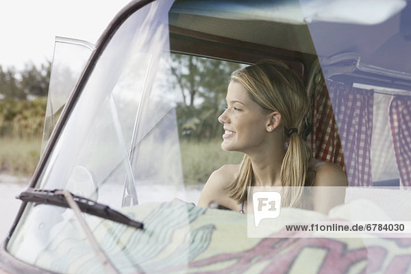 Young woman sitting in van on beach