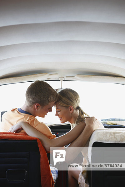 Young couple sitting in van on beach