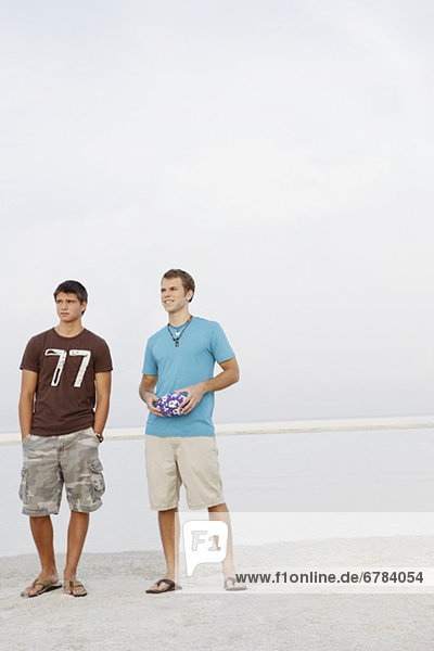Young men standing on beach with football