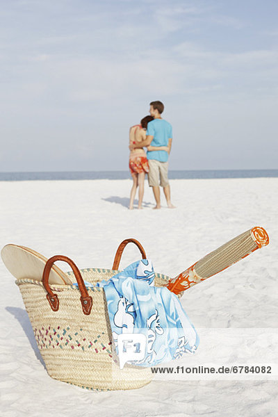 Young couple and beach essentials on beach
