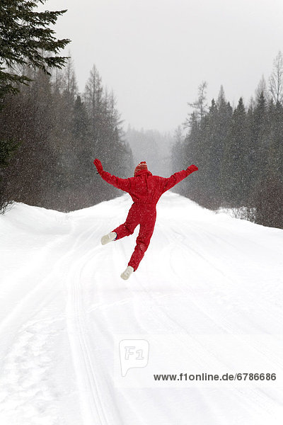 Senior woman leaping for joy in the snow  Algonquin Park  Ontario