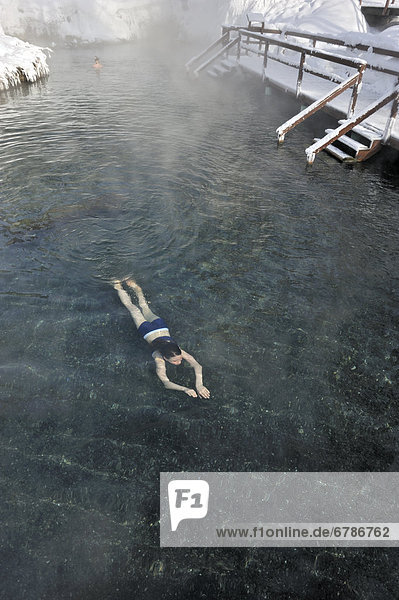 A young girl swimming in hot springs in mid winter  Liard River Hot Springs  Northern British Columbia