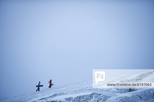 Mother and daughter climbing hill to snowboard down  Dempster Highway  Yukon