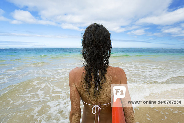 Hawaii  Kauai  Woman holding surfboard on beach  View from behind.