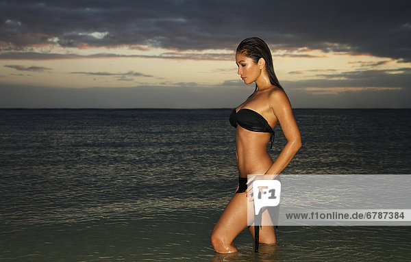 Hawaii Oahu schöne Frau stehend in Meerwasser bei Sonnenuntergang.