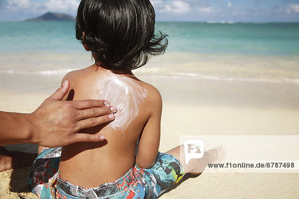 Hawaii  Oahu  übergeordnete Element putting Sonnenschutzmittel Lotion auf Kindes zurück am Strand