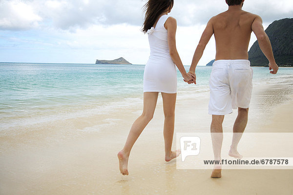 Hawaii  Oahu  Waimanalo  junges Paar hält hände  die zusammen entlang dem Strand