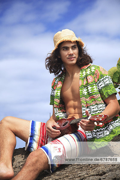 Hawaii  Oahu  Young male mit Vintage hat aloha Shirt und Stroh entspannenden halten einer Ukulele.