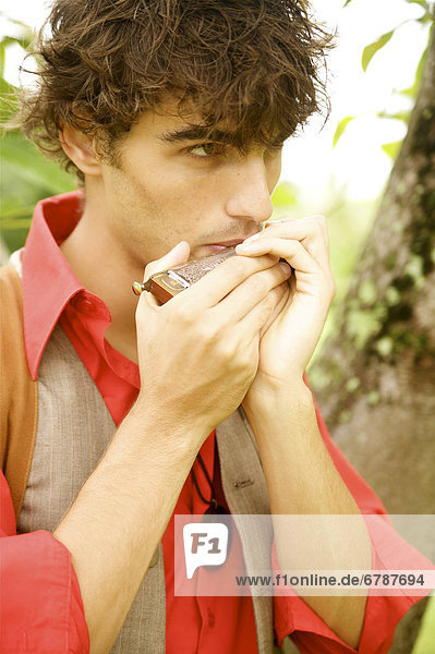 Hawaii  Portrait of a European Male Model playing a harmonica.