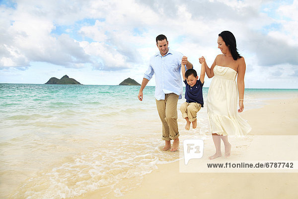 Hawaii  Oahu  Lanikai  Young Family holding hands strolling along the beach.