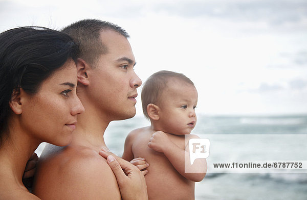 Hawaii  Oahu  Profile portrait of young attractive family of three looking out at the ocean.