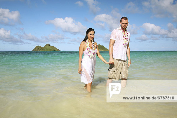 Oahu  Hawaii  Lanikai  Young couple both holding hands and walking out of water.