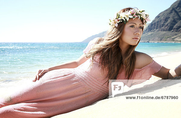 Hawaii  Oahu  Kaena Point  Attractive local girl lounging on the beach in pink dress.
