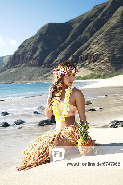 Hawaii  Oahu  Kaena Point  Attractive hula girl sitting on beach.