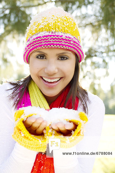 Woman wearing winter clothing in snowy environment  Holding snow in hands.