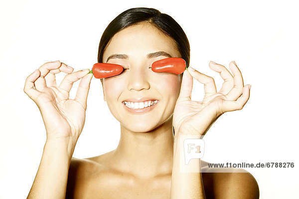 Hawaii  Studio Headshot of ein schönes Mädchen halten Paprika über ihre Augen.