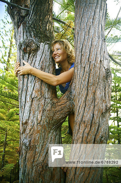 Hawaii  Kauai  Hanalei  Portrait einer schönen Frau umarmt einen Baumstamm.