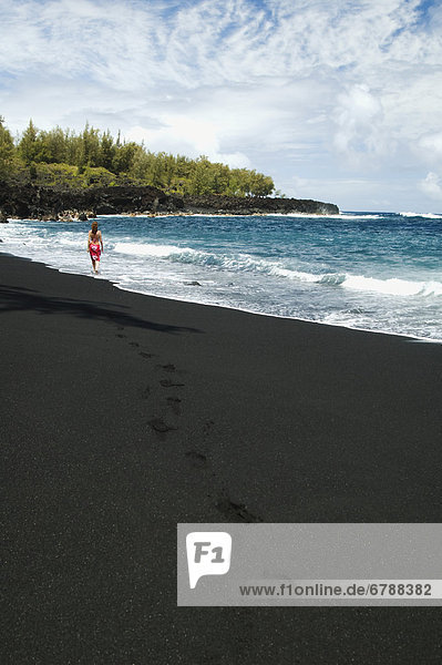 Hawaii  Big Island  Pololu Valley Black Sand Beach  Frau stehend in der Shorebreak.