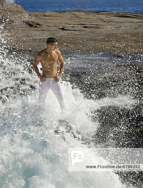 Hawaii  Oahu  Male wearing white pants on rocky cliff.