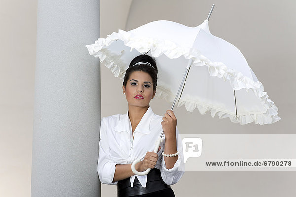 Junge Frau mit Hochsteckfrisur  weißem Schirm und weißem Hemd