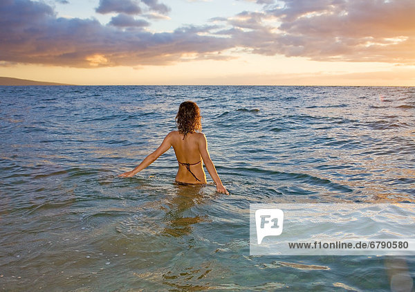 Hawaii  Kauai  Frau zu Fuß in den Ozean als die Sonne-Sets.