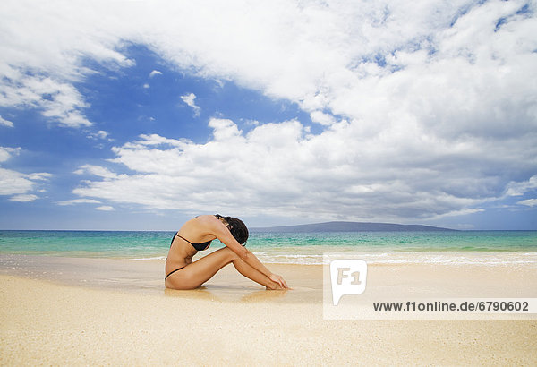 Hawaii  Frau sitzt am Strand in tropischen Remotespeicherort.
