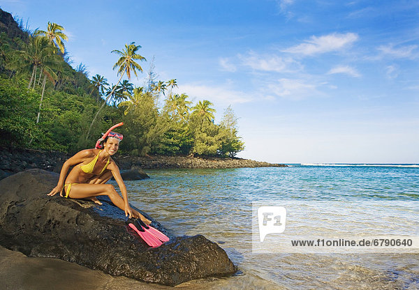Hawaii  Kauai  Kee Beach  Woman with snorkel gear smiling on a rock.