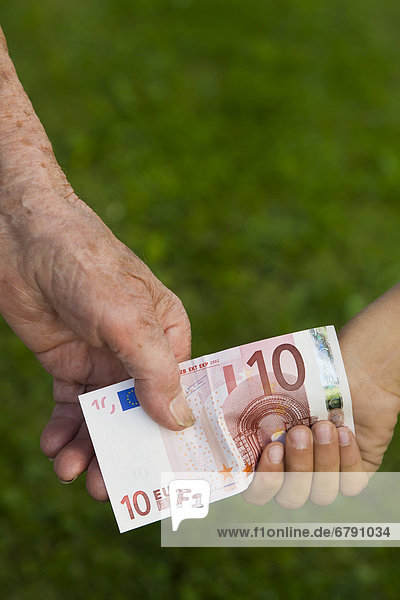 Kind und alte Frau halten einen 10-Euro-Schein