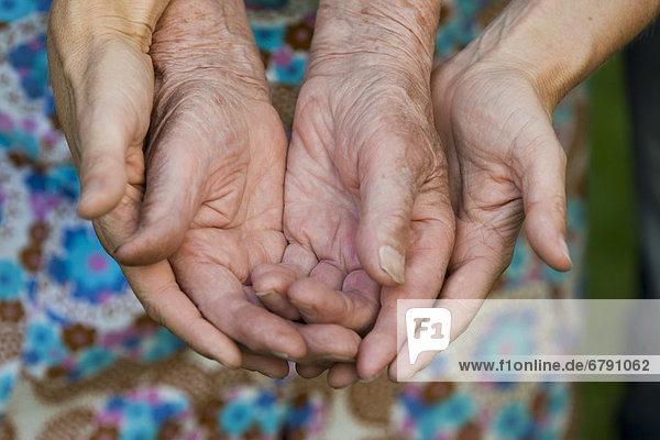 Händer einer erwachsenen und einer alten Frau
