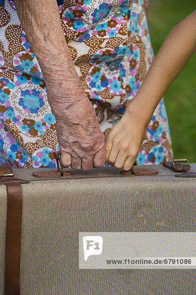 Alte Frau und Kind halten Koffer