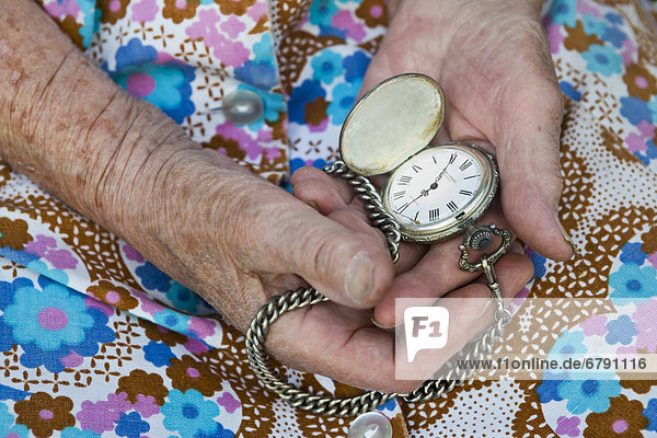 Alte Frau hält alte Taschenuhr in den Händen