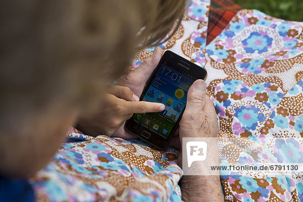 Kind zeigt alter Frau etwas auf einem Smartphone