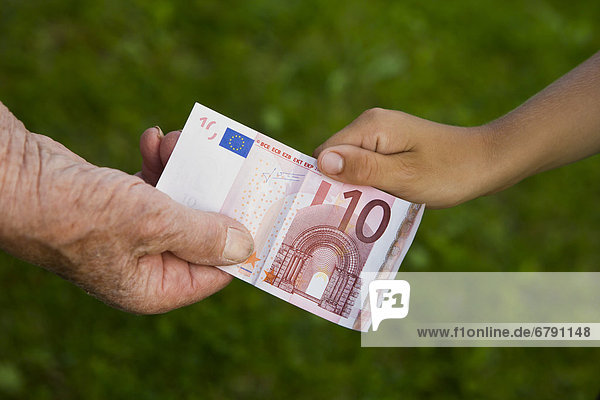 Kind und alte Frau ziehen an einem 10-Euro-Schein