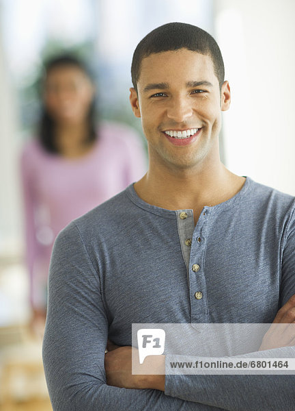 Portrait of man smiling  woman in background