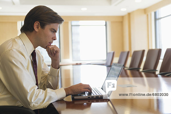 Businessman using laptop in board room