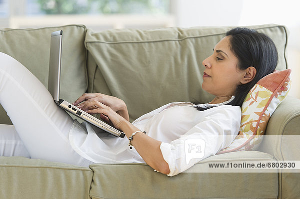 Frau liegend auf Sofa mit laptop