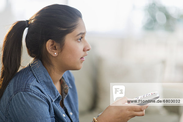 Girl (12-13) holding remote control