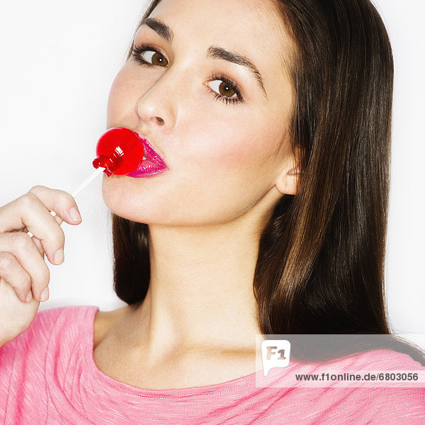 Studio portrait of young woman licking lollypop