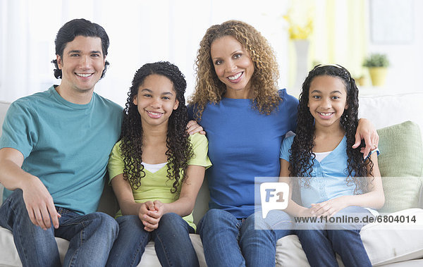 Portrait of parents with daughters (10-13) sitting on sofa
