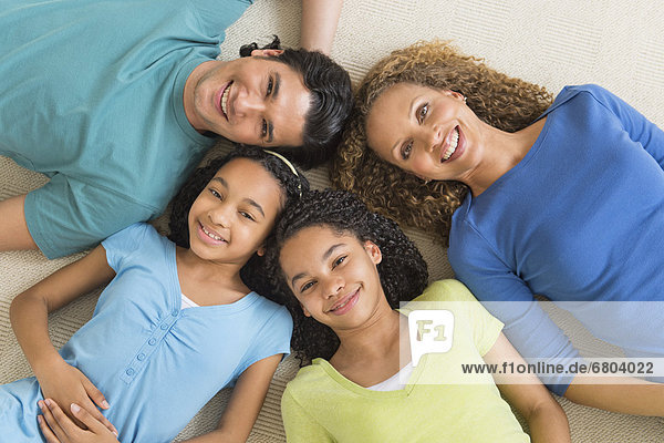 Portrait of parents with daughters (10-13) lying on floor