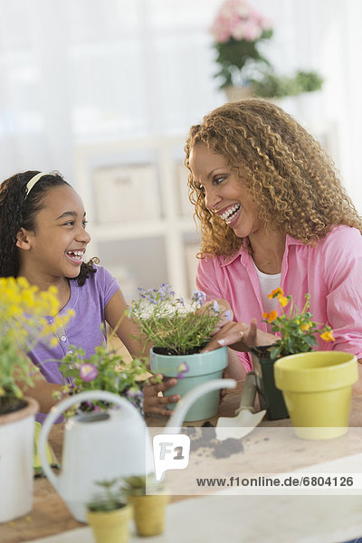 Mother with daughter (12-13) potting flowers