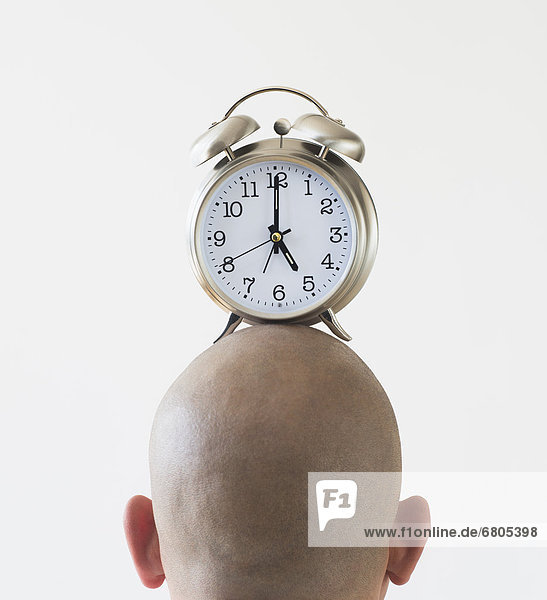 Back view of man with alarm clock on shaved head