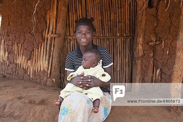 Außenaufnahme Frau Wohnhaus halten Afrika Baby Mosambik