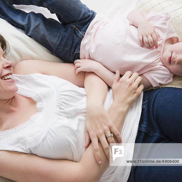 Mother and daughter (2-3) lying in bed