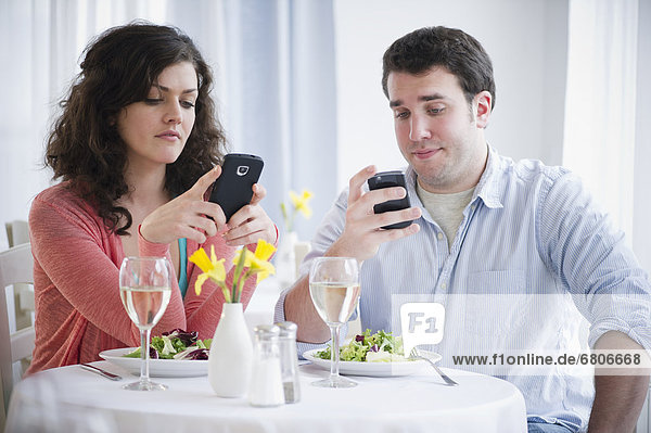 Couple having dinner and text messaging