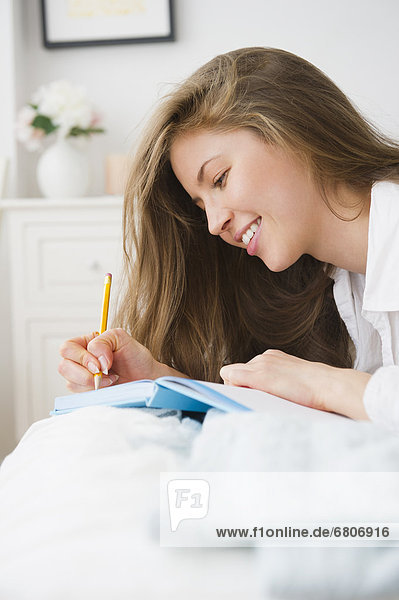 Woman lying on bed and writing diary