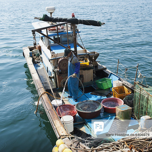 A Fisherman Stands On A Fishing Boat In The Water  Busan Korea
