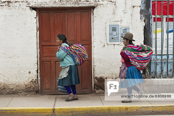 Two Women Walking On A Sidewalk Carrying Blanket Bundles From The Market  Cusco Peru