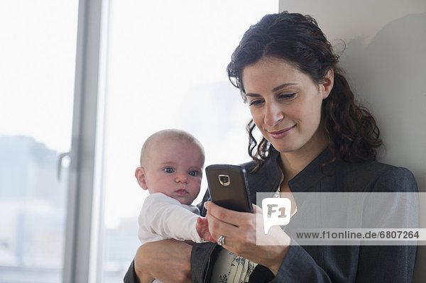Mother with baby boy (2-5 months) text messaging
